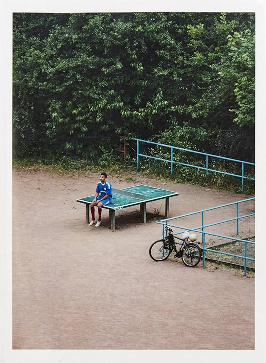 Person playing ping pong outdoors with a bicycle nearby