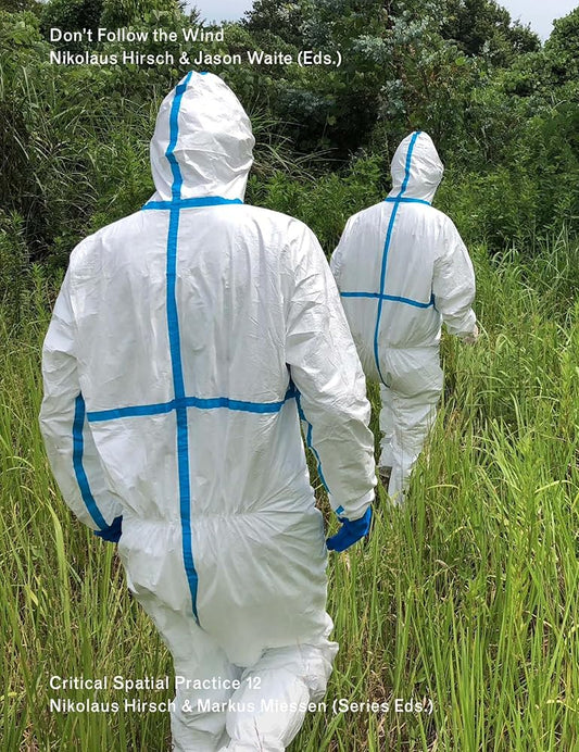 Two individuals wearing protective white suits with blue zippered fronts, standing in a grassy outdoor area.
