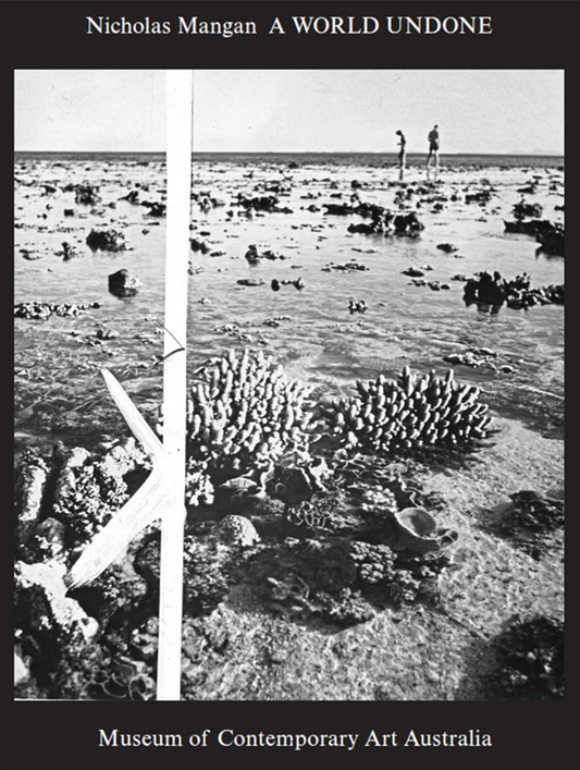 Book cover for 'Nicholas Mangan: A World Undone' featuring a black and white photograph of a beach scene with coral reefs and a person in the background.