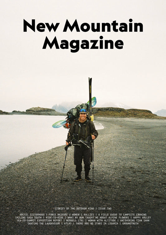 Person with skis and backpack on a mountain landscape with 'New Mountain Magazine' text.