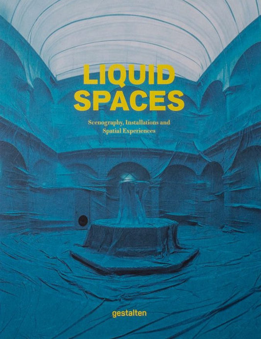 Book cover of "Liquid Spaces", with yellow text over a picture of a room covered in blue fabric
